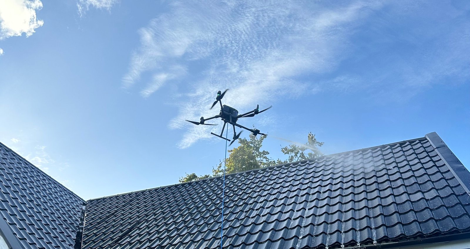 Skywash drönare tvättar ett tak mot blå himmel